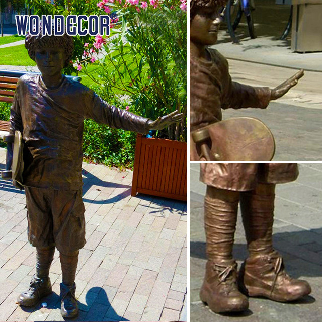A bronze metal art sculpture of a boy holding a skateboard outdoors