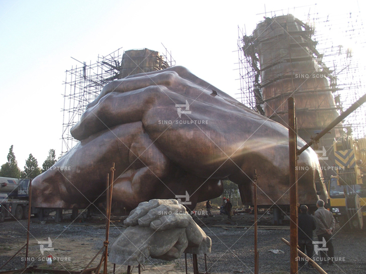 Bronze monumental sculpture sections are lifted and assembled at the site.