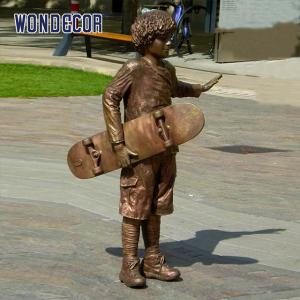 China A bronze metal art sculpture of a boy holding a skateboard outdoors wholesale