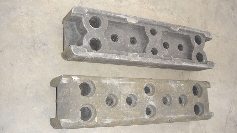Two rubber temporary fence feet on the ground. They display the positive and back sides of the rubber temporary fence feet.