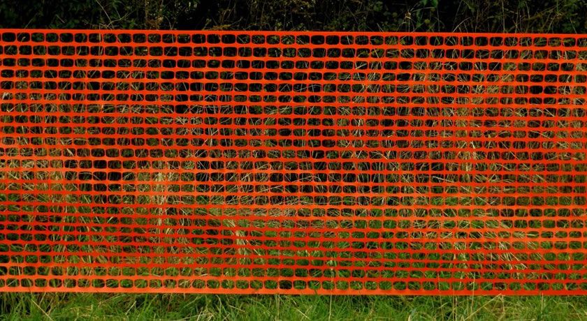A piece of orange plastic fence with oval hole is being put into use.